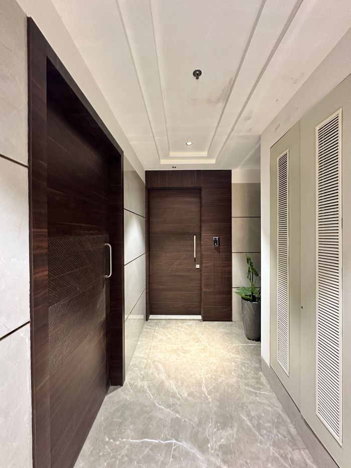 Stylish hallway featuring a wooden door and sleek interiors with natural lighting.